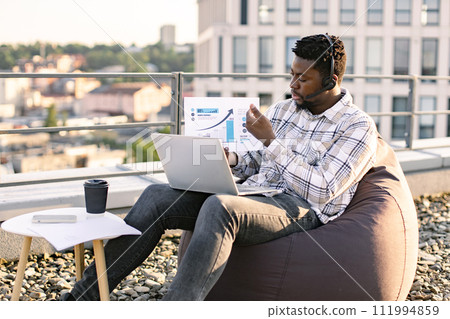African male giving online presentation using headset and computer. African male giving online presentation using headset and computer. 111994859