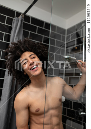 Young man having a shower and looking pleased and joyful Young man having a shower and looking pleased and joyful 111995249