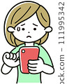A woman with a troubled expression while operating a smartphone 111995342