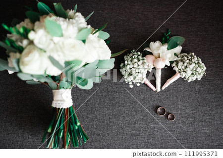 Wedding rings and a bouquet of roses and other flowers 111995371