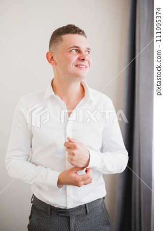 Grooms morning preparation. Handsome man getting dressed and preparing for the wedding 111995374
