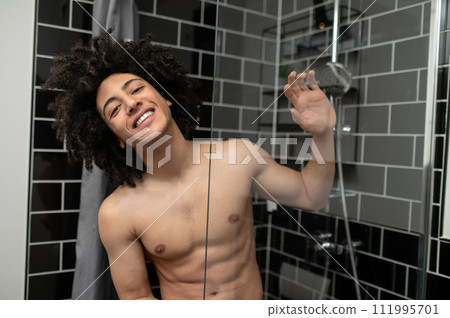 Young man having a shower and looking pleased and joyful Young man having a shower and looking pleased and joyful 111995701
