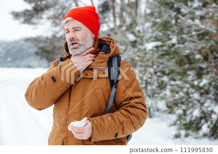 Man in a winter forest looking sick and got sore throat 111995830