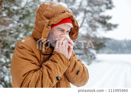 Man in a winter forest looking sick and unwell Man in a winter forest looking sick and unwell 111995860