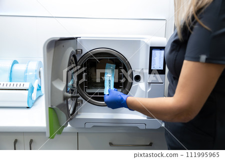 Doctor doing sterilization procedure hands in blue gloves holding dentist tools Doctor doing sterilization procedure hands in blue gloves holding dentist tools 111995965
