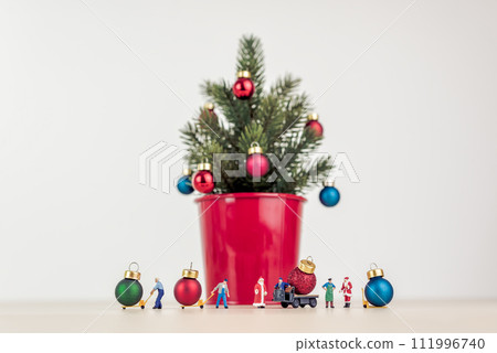 Miniature people decorating giant Christmas tree 111996740