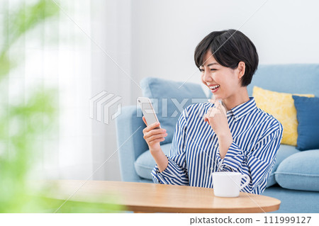 一個在客廳裡操作智能手機的女人。 111999127