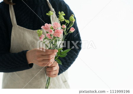 A woman in an apron holding a carnation 111999196