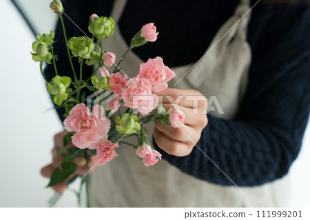 A woman in an apron holding a carnation A woman in an apron holding a carnation 111999201
