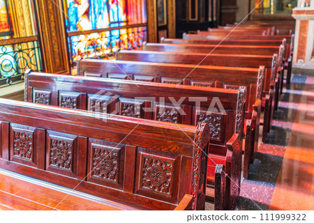 Empty wooden church benches of a Christian church. Blurry alter in the background. Selective focus. Concept of church service or empty churches. Empty wooden church benches of a Christian church. Blurry alter in the background. Selective focus. Concept of church service or empty churches. 111999322