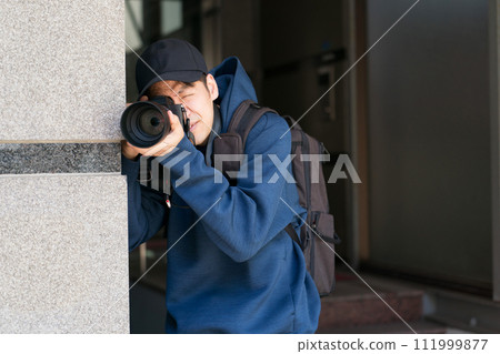 A person hiding in a building and taking a photo 111999877