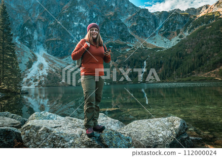 Shot of woman traveler relaxing alone travel in adventure vacation with backpack enjoying standing on the top of the mountain near Famous mountains lake Morskie oko or sea eye lake In High Tatras 112000024