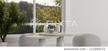A marble coffee table, poufs, and a houseplant near by the window in a modern white living room. 112000252