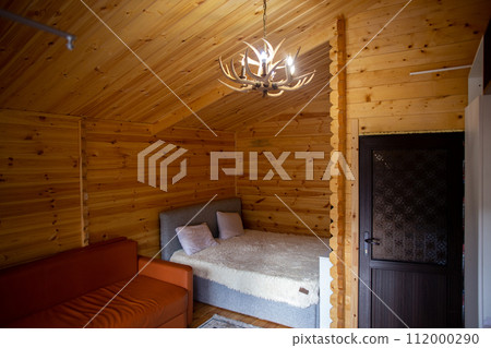 Rustic wooden cabin interior with bed, sofa, and armoire Rustic wooden cabin interior with bed, sofa, and armoire 112000290