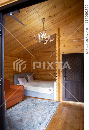 Rustic wooden cabin interior with bed, sofa, and armoire 112000292