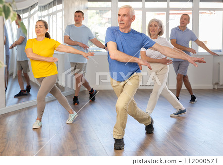 Elderly man learning dynamic dances at group choreography lesson 112000571