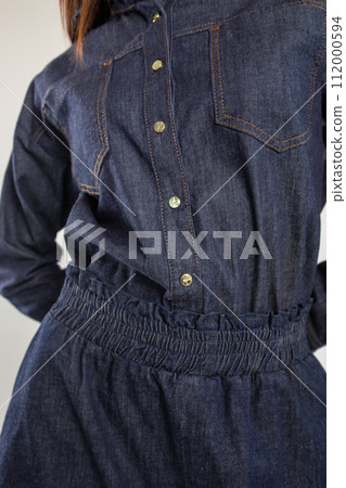 Elegant woman in a blue denim shirt dress with a collar and long sleeves 112000594