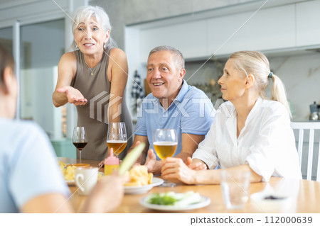 Happy seniors chatting at dinner table. Concept of happy life together in nursing home 112000639
