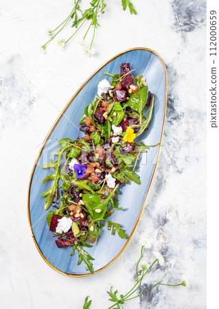 top view organic baby greens salad with beetroot, goat cheese, pistachios and citrus dressing 112000659