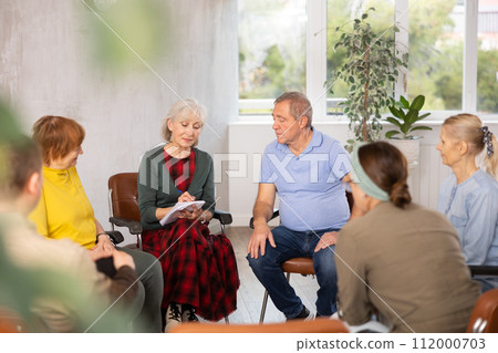 Aged woman conducting language speaking club for older adults 112000703