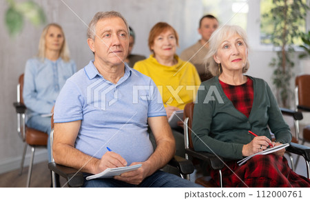 Older male and female students listening to lecture in university 112000761