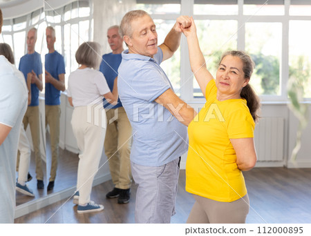 Elderly woman with male partner in latin dance class. Social dancing concept 112000895