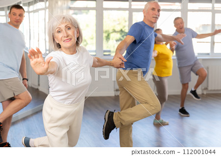 Mature men and women learn energetic twist dance in choreography studio 112001044