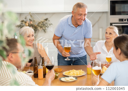 Old men and women talking merrily while having snack in the kitchen 112001045