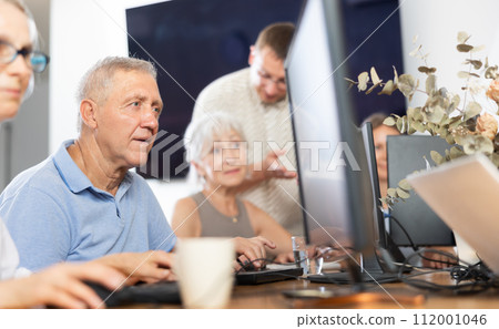 Focused older gentleman using computer at internet cafe 112001046