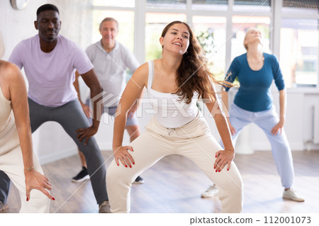 Young woman teaching hip hop to group of multiethnic mature people 112001073