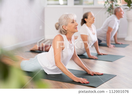 Mature lady performs asana cobra - pose dog muzzle up, Urdhva Mukha Shvanasana- Bhujangasana Mature lady performs asana cobra - pose dog muzzle up, Urdhva Mukha Shvanasana- Bhujangasana 112001076