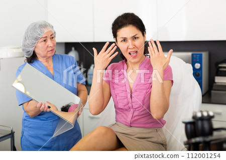 Portrait of an outraged young female patient in a clinic after procedures Portrait of an outraged young female patient in a clinic after procedures 112001254