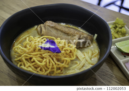Thai noodles Khao Soi, spicy curry with seasoning on table Thai noodles Khao Soi, spicy curry with seasoning on table 112002053