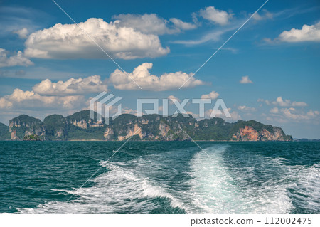 Tropical islands view behind speed boat with ocean blue sea water and white sand beach at Railay Beach, Krabi Thailand nature landscape 112002475