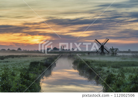 Small Dutch Windmill and field sunrise at Zaanse Schans Village, Amsterdam Netherlands 112002506