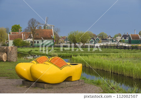 Zaanse Schans, Netherlands - May 1, 2023: Dutch Windmill and traditional house with wood shoes in village Zaanse Schans, Netherlands - May 1, 2023: Dutch Windmill and traditional house with wood shoes in village 112002507
