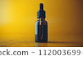 A single amber dropper bottle against a vibrant yellow background, showcasing a minimalist aesthetic. 112003699