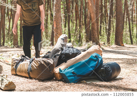 A male camper packs, prepares, and dismantles his belongings at a forest site at a campsite. A male camper packs, prepares, and dismantles his belongings at a forest site at a campsite. 112003855