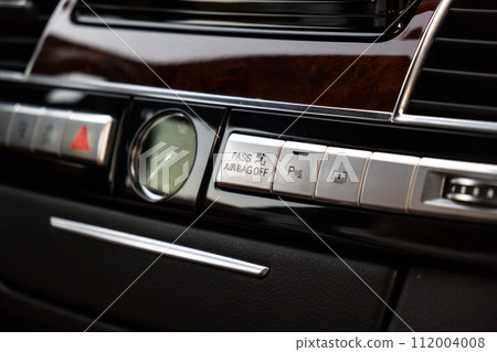 Interior of modern luxury car. Details of automatic transmission gear shift, multimedia control system, car control panel, Air Vent Red emergency button and dashboard inside. Prestige sport automobile Interior of modern luxury car. Details of automatic transmission gear shift, multimedia control system, car control panel, Air Vent Red emergency button and dashboard inside. Prestige sport automobile 112004008