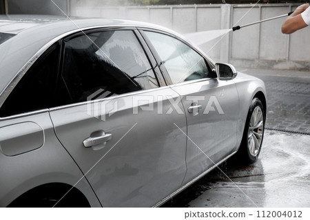 Washing luxury silver car on touchless car wash. Washing sedan car with foam self-service and high pressure water. Winter cleaning in car wash. Cleanliness environment Washing luxury silver car on touchless car wash. Washing sedan car with foam self-service and high pressure water. Winter cleaning in car wash. Cleanliness environment 112004012