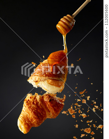 Croissant with honey in air on a black background. Croissant with honey in air on a black background. 112005600