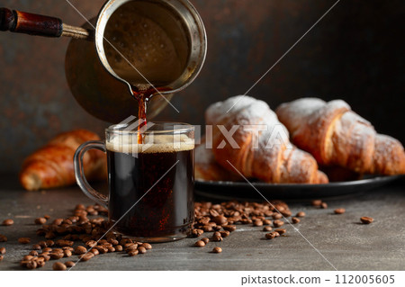 Croissants and black coffee on a kitchen table. 112005605