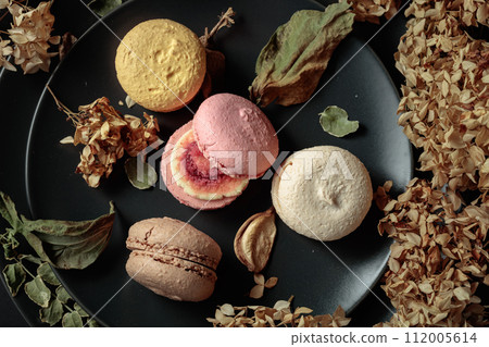 Macaroons with dried flowers on a black plate. Macaroons with dried flowers on a black plate. 112005614