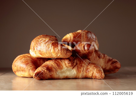 Freshly baked croissants on a beige ceramic table. 112005619