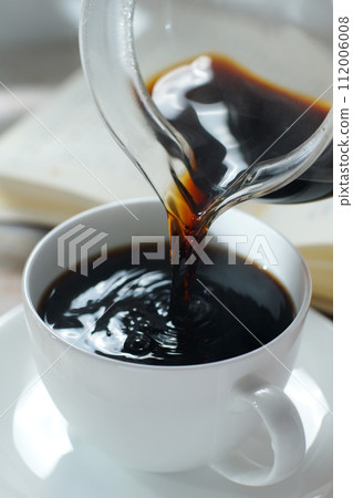 Pouring coffee into a coffee cup Break time while reading 112006008