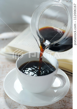 Pouring coffee into a coffee cup Break time while reading Pouring coffee into a coffee cup Break time while reading 112006167