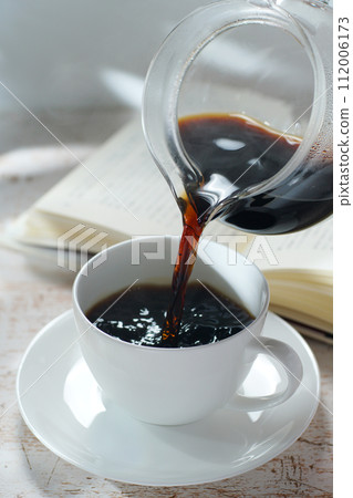 Pouring coffee into a coffee cup Break time while reading 112006173