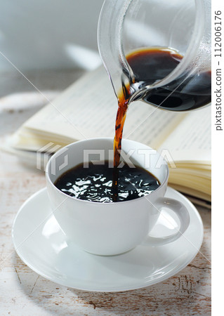Pouring coffee into a coffee cup Break time while reading 112006176