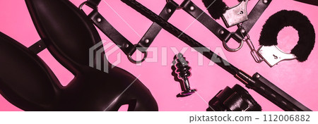 set of BDSM sex toys with handcuffs, whip flogger, butt anal plug for submission and domination on a pink background set of BDSM sex toys with handcuffs, whip flogger, butt anal plug for submission and domination on a pink background 112006882
