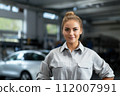 Smiling female technician in dealership. Professional young woman in car dealership smiles with confidence, embodying the shift towards a more inclusive and diverse automotive industry. 112007991